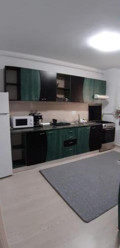 cocina con armarios verdes y nevera blanca en apartament, en Floreşti