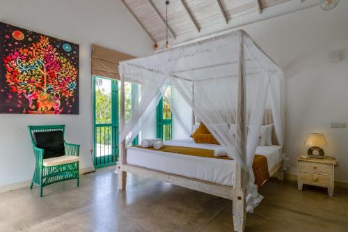 a bedroom with a canopy bed and a chair at Astig Villa - Negombo in Negombo