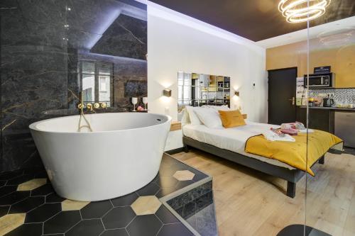 La salle de bains est pourvue d'une baignoire à côté d'un lit. dans l'établissement Love Avenue 51 - Studio proche du centre, à Reims