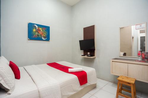 1 dormitorio con 1 cama y TV en RedDoorz near Binus Anggrek 2, en Yakarta