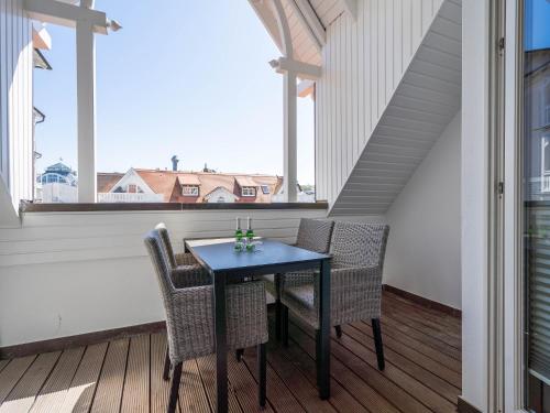 einen Tisch und Stühle auf einem Balkon mit einem großen Fenster in der Unterkunft Strandvillen Binz - Ferienwohnung mit 1 Schlafzimmer und Balkon AH-723 in Binz