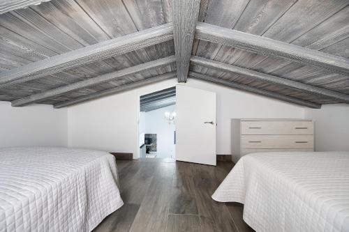 Duas camas num quarto branco com tectos em madeira em Ferro Piscina Climatizada 1 Diciemb em Chiclana de la Frontera