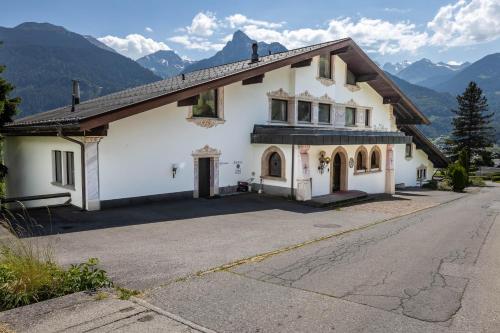 a large white house with mountains in the background at keyone rooms Montafon in Schruns-Tschagguns