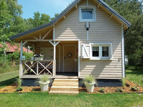 a tiny house with a porch and stairs in a yard at Chatka Jezioranka & bania in Kolonia Siedlątków