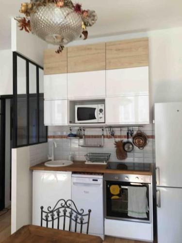 eine Küche mit einem weißen Kühlschrank und einer Mikrowelle in der Unterkunft Aux portes des Jeux Olympiques,Vincennes,un nid cosy in Vincennes