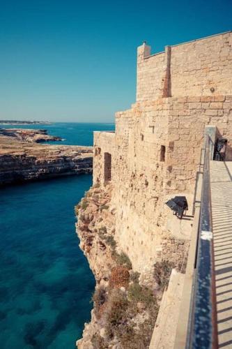 a stone wall next to the water next to a building at Aquatica Home in Polignano a Mare