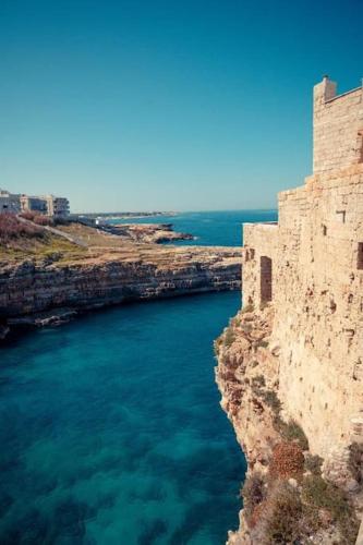 a castle on the side of a cliff next to the water at Aquatica Home in Polignano a Mare
