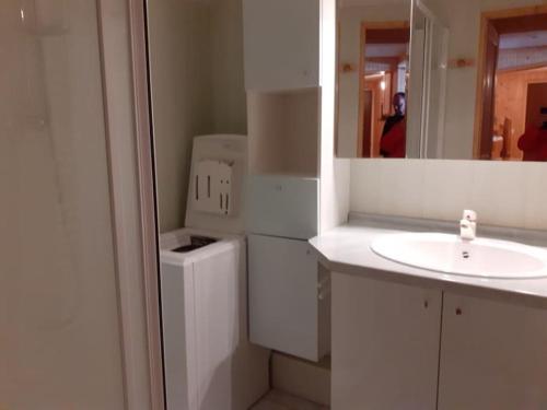 ein weißes Badezimmer mit einem Waschbecken und einem Spiegel in der Unterkunft Grand appartement au pied des pistes au cœur des Rousses in Les Rousses