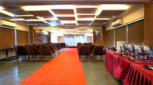 a conference room with red tables and chairs and a red carpet at Hotel Maharaja in Nashik