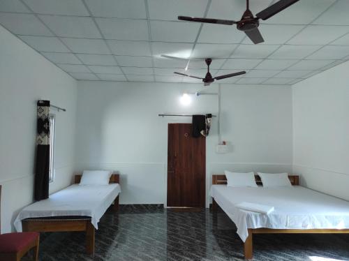 Jyoti GaonにあるFalcon Jungle Resortのベッド2台と天井ファンが備わる客室です。
