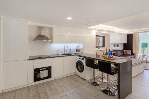 プラヤ・デル・イングレスにあるModern & Elegant Loftのキッチン(白いキャビネット、食器洗い機付きカウンター付)