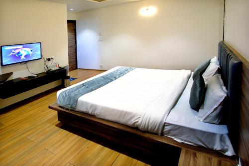 a bedroom with a bed and a flat screen tv at Hotel Maharaja in Nashik