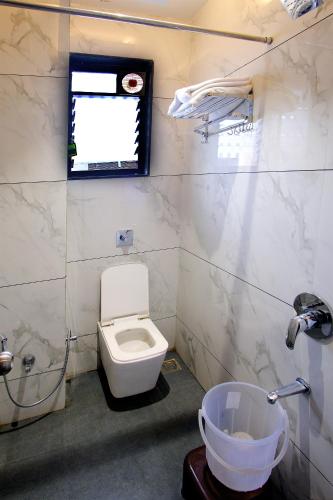 a bathroom with a toilet and a window and a sink at Hotel Maharaja in Nashik