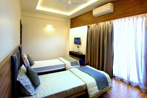 a bedroom with two beds and a window at Hotel Maharaja in Nashik