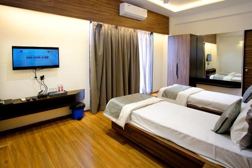 a hotel room with two beds and a flat screen tv at Hotel Maharaja in Nashik