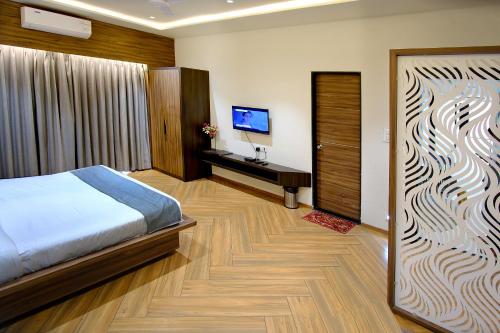 a bedroom with a bed and a desk and a television at Hotel Maharaja in Nashik