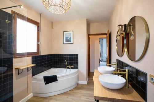 a bathroom with two sinks and a tub and a mirror at La Villa Maxine, vue mer et spa in Criel-sur-Mer