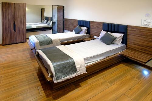 two beds in a room with wooden floors at Hotel Maharaja in Nashik