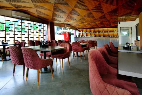 a dining room with red chairs and tables in a restaurant at Hotel Maharaja in Nashik