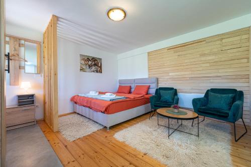 a bedroom with a bed and two chairs and a table at Apartments CENTER OF THE WORLD in Žabljak