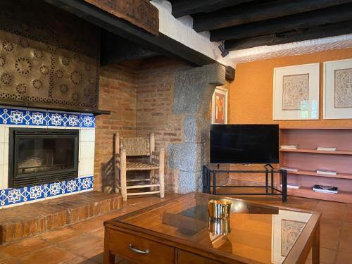 a living room with a fireplace and a television at Finca Valdegrullas in Candeleda