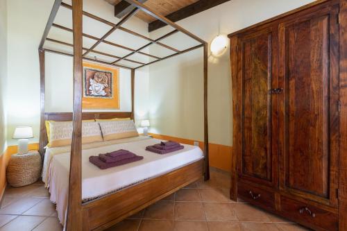Studio Lo Scrigno في بورتو توريس: غرفة نوم مع سرير مظلة وخزانة خشبية