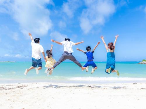 a group of people jumping in the air on the beach at Saraswati in Nakijin