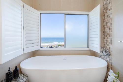a white tub in a bathroom with a window at Laguna La Crete 26 in Uvongo Beach