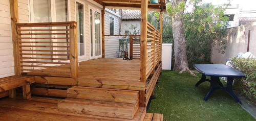 une terrasse en bois avec un banc sur le côté d'une maison dans l'établissement Mobil-Home VA 04 à Vias - La Carabasse - Camping Siblu avec piscine, à Vias