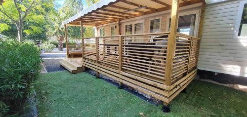 une maison avec une terrasse en bois sur le côté de celle-ci dans l'établissement Mobil-Home VA 04 à Vias - La Carabasse - Camping Siblu avec piscine, à Vias