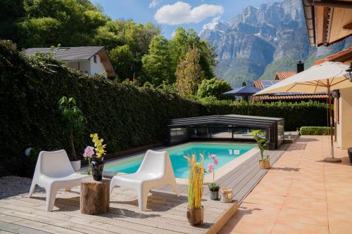 a swimming pool with two chairs and a table at Doodle's Amazing Chalet -Walensee - Flumserberg - Churfirsten - Heidiland - Pool - Sauna in Mols