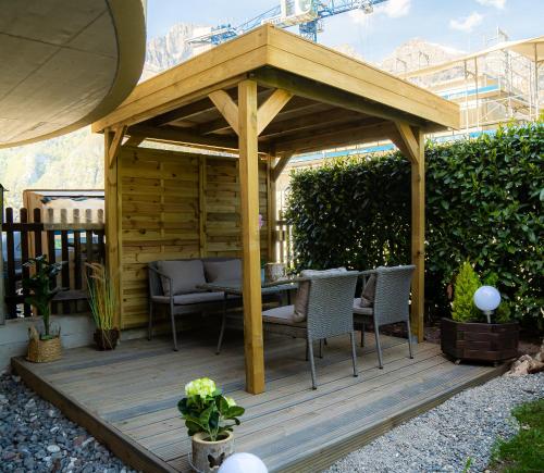 a wooden pergola with chairs and a table on a deck at Doodle's Amazing Chalet -Walensee - Flumserberg - Churfirsten - Heidiland - Pool - Sauna in Mols
