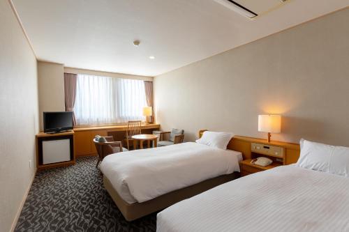 久留米市にある萃香園ホテルのベッド2台とテレビが備わるホテルルームです。
