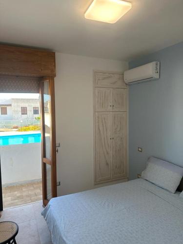 Un dormitorio con una cama y una puerta a una piscina. en CASA APPRODO, en Porto Cesareo