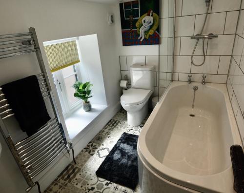a bathroom with a bath tub and a toilet at Bloomsbury House - Magical Coastal Retreat - Crabpot Cottages in Sheringham