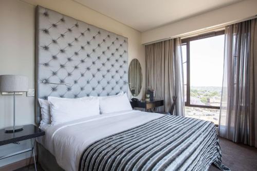 a bedroom with a large bed and a large window at Southern Sun Hyde Park Sandton in Johannesburg