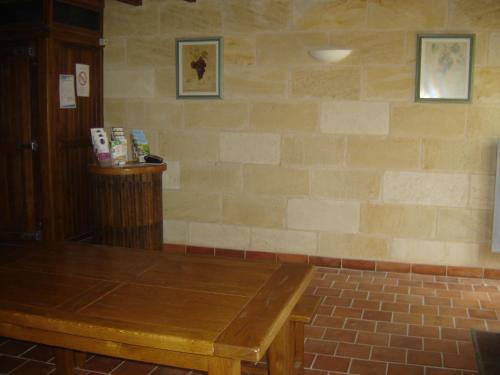 een kamer met een houten tafel en een bakstenen muur bij Château Laborde Caudalie in Saint-Médard-de-Guizières
