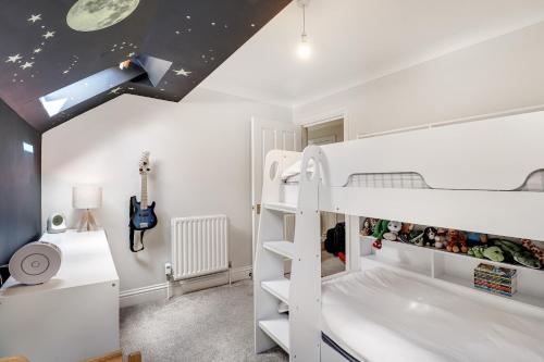 ein Kinderschlafzimmer mit einem weißen Etagenbett und einer Gitarre in der Unterkunft Pass the Keys Perfectly presented house in Sevenoaks