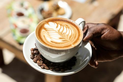 a person holding a cup of coffee on a plate at Mr Kahawa in Paje