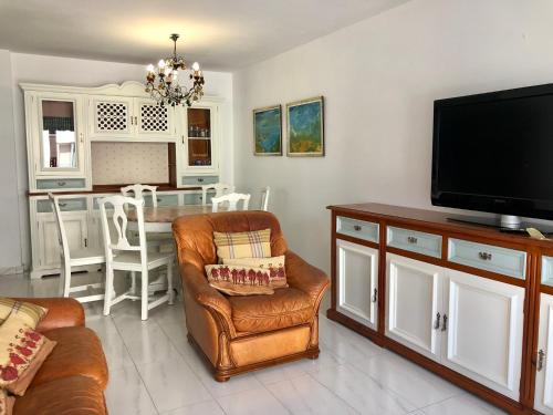 een woonkamer met een bank, een televisie en een tafel bij Apartamento céntrico en la playa de Bueu in Bueu