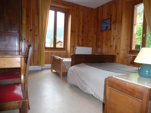 a bedroom with a bed and a desk and windows at L'Horizon des Alpes in Le Petit-Bornand-lès-Glières