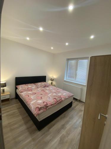 a bedroom with a bed with a pink comforter at Apartmán Levandule in Mařenice
