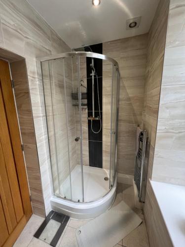 a shower with a glass door in a bathroom at Edgerton Suites in Huddersfield