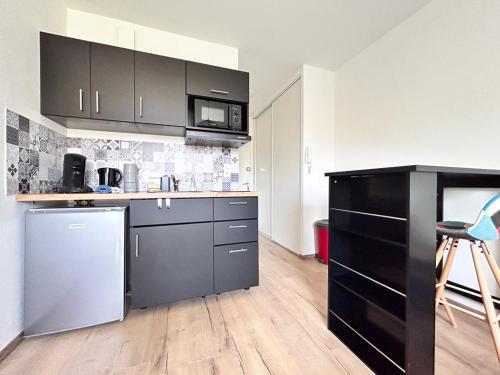 une cuisine avec des armoires noires et un réfrigérateur en acier inoxydable dans l'établissement Studio confortable et lumineux proche des hôpitaux - Hotel de ville Beaumont, à Beaumont