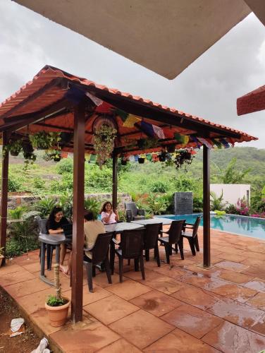 a group of people sitting at tables under a pergola at Rajput Farm in Alibaug
