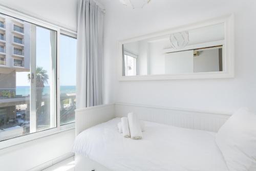 biała sypialnia z oknem i łóżkiem z ręcznikami w obiekcie Sea View 2 bedroom apartment with Bomb Shelter w Tel Awiwie