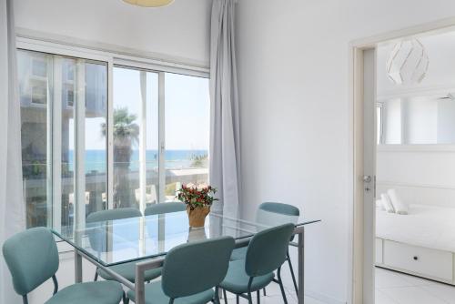 uma sala de jantar com uma mesa de vidro e cadeiras azuis em Sea View 2 bedroom apartment with Bomb Shelter em Tel Aviv
