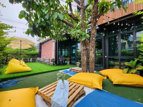 a patio with yellow pillows and a tree at Wayha Hostel Don Mueang Airport in Bangkok