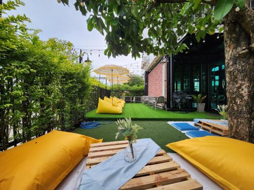 a patio with a table and yellow pillows and a tree at Wayha Hostel Don Mueang Airport in Bangkok