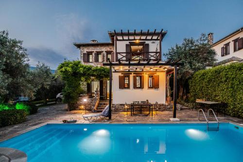 a house with a swimming pool in front of a house at Villa 10 Elies in Koropi
